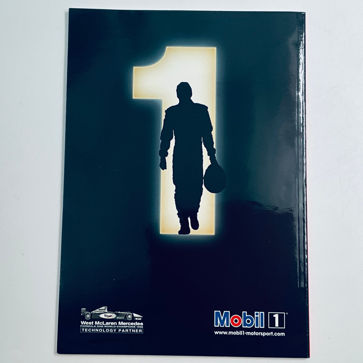 Racing magazine cover with dark silhouette of a driver holding a helmet