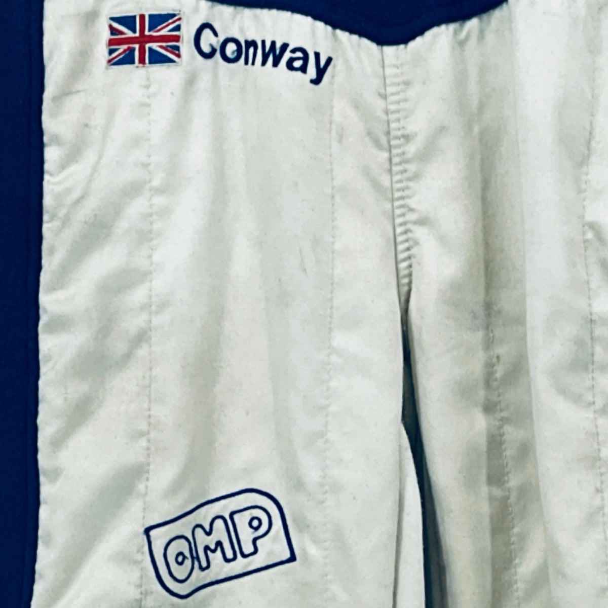Race driver suit lower leg area with "OMP" patch on white fabric