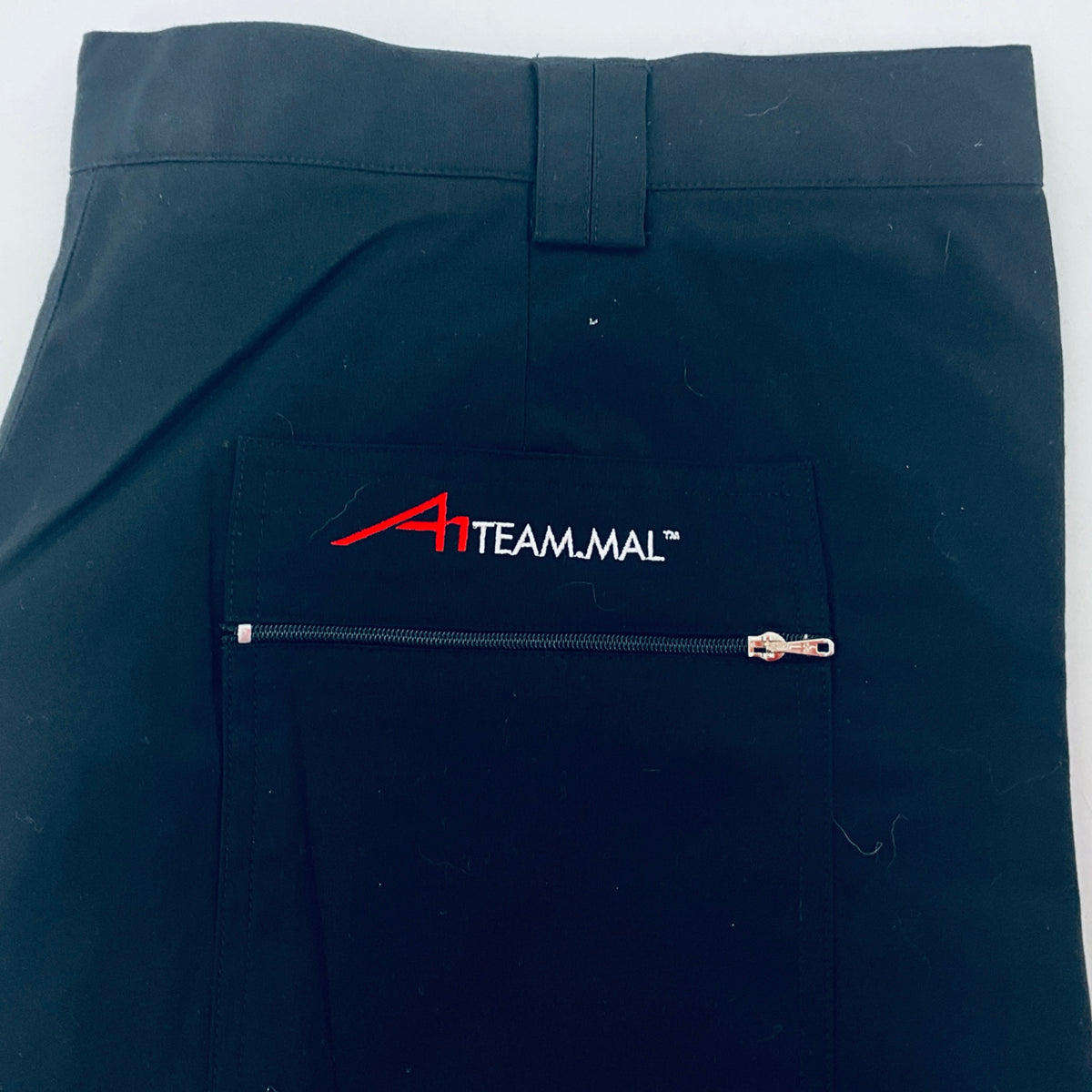 Navy shorts close-up: TEAMMAL logo and zip pocket