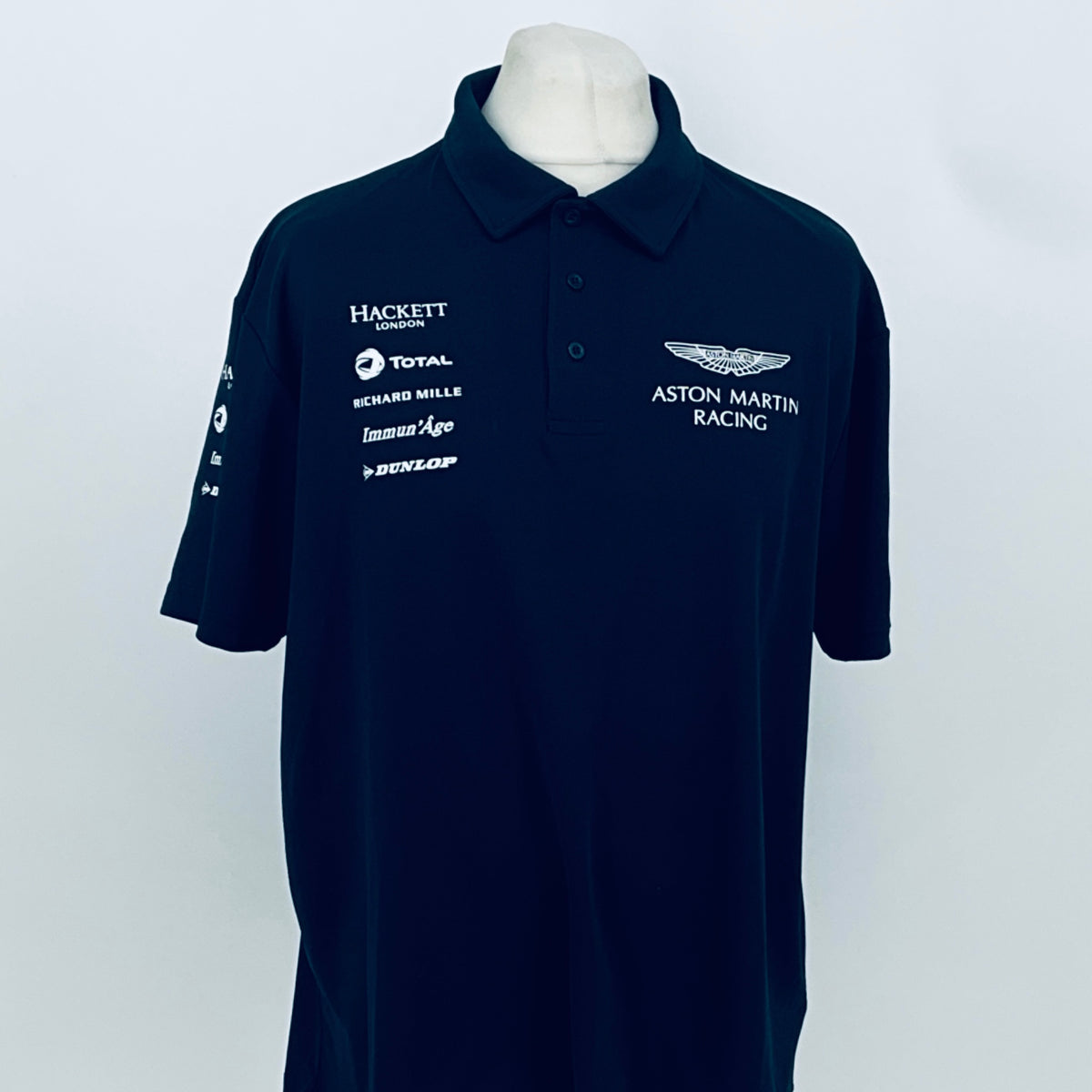 Navy Aston Martin Racing team polo shirt with sponsor logos on chest and sleeve.