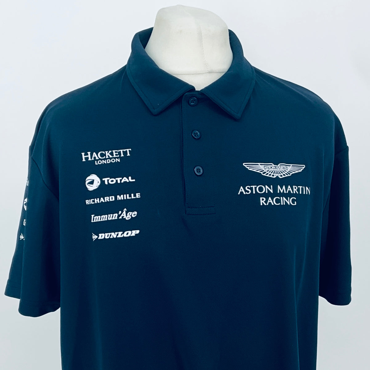 Teal Aston Martin Racing polo shirt with Hackett London and sponsor logos on chest.