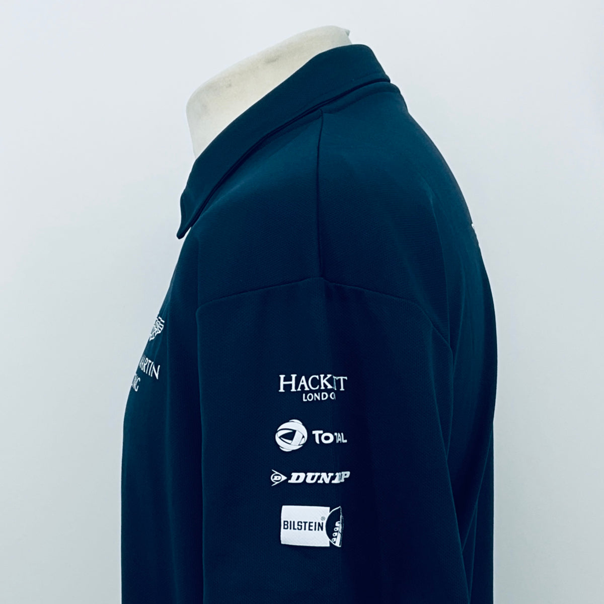 Teal Aston Martin Racing polo shirt with rear sleeve sponsor logos on side view.