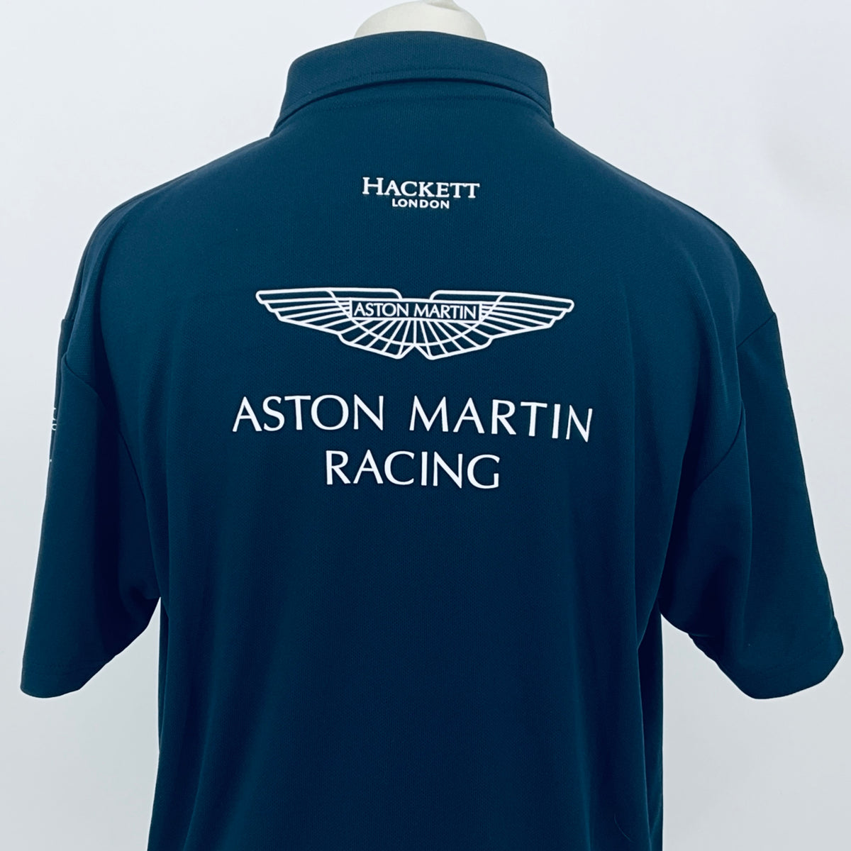 Teal Aston Martin Racing polo shirt, back view with winged Aston Martin emblem and HACKETT.