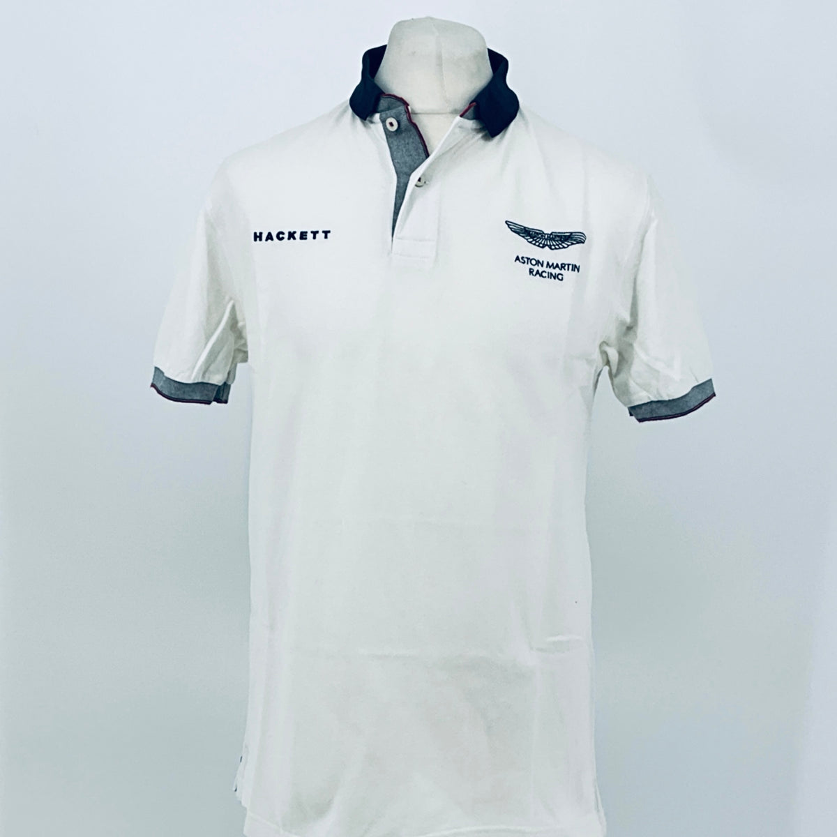 White polo shirt with navy collar, trim, and racing logo on chest