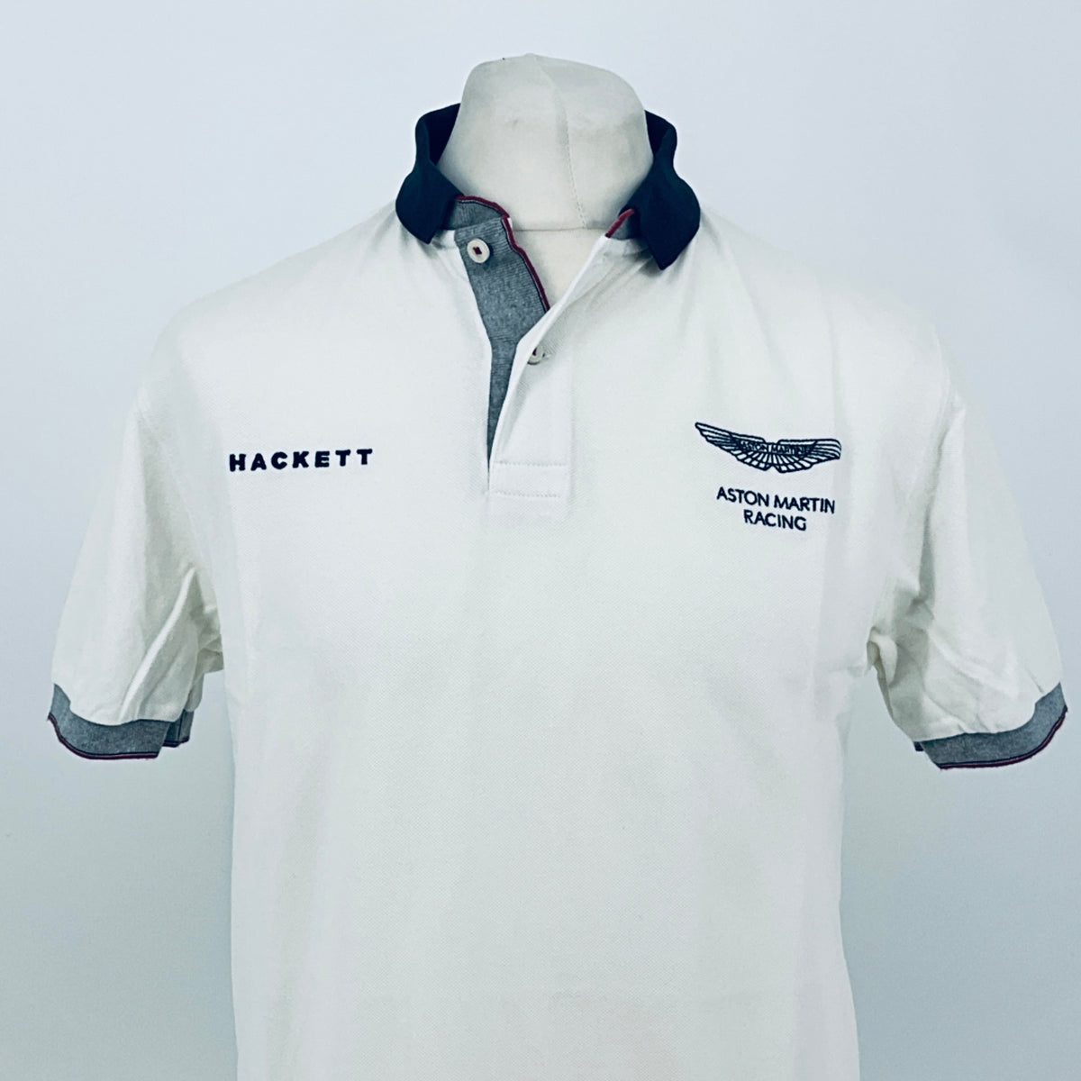White polo shirt with navy collar and Aston Martin Racing chest emblem