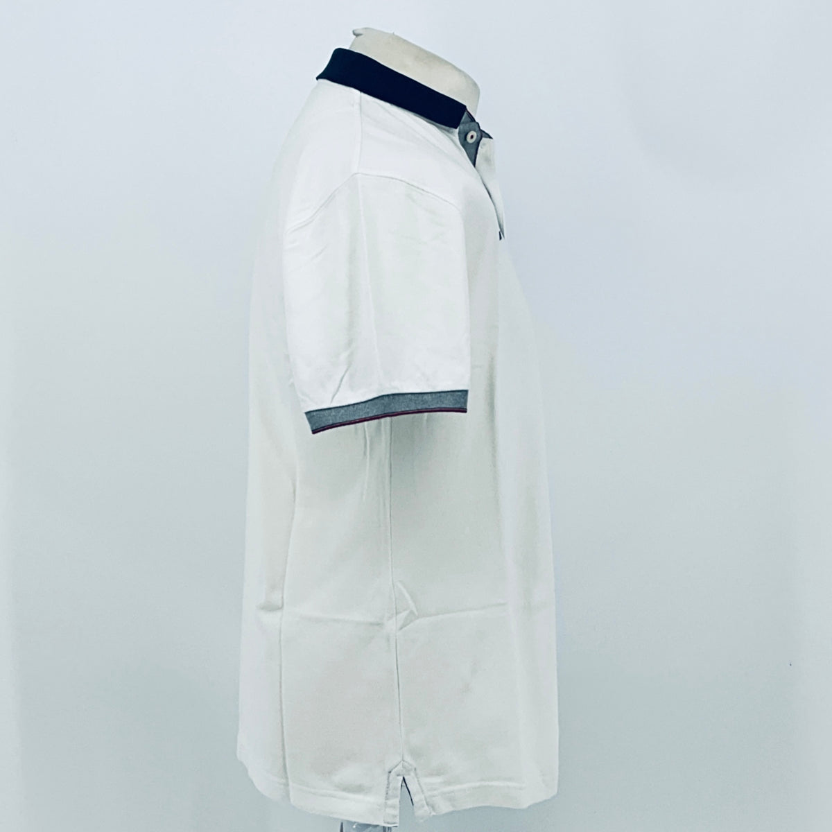 White polo shirt back/side view with navy collar and dark stripe sleeve hem