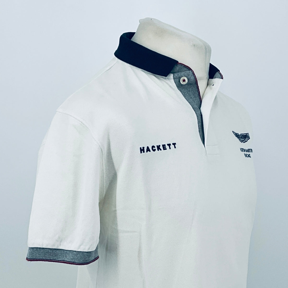 White polo shirt 3/4 front view with navy collar and Hackett chest logo