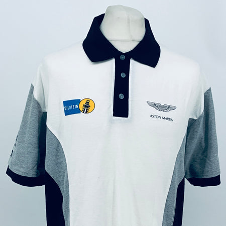White polo shirt with navy collar and front buttons, gray sleeves, Aston Martin and sponsor logos