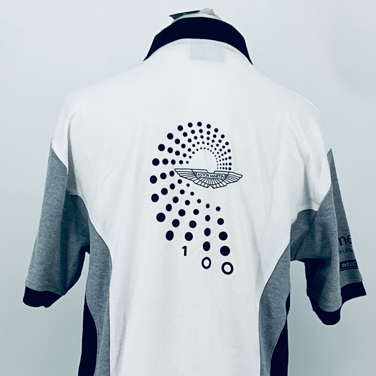 Back view of white polo shirt with navy collar, dotted Aston Martin logo and race numbers