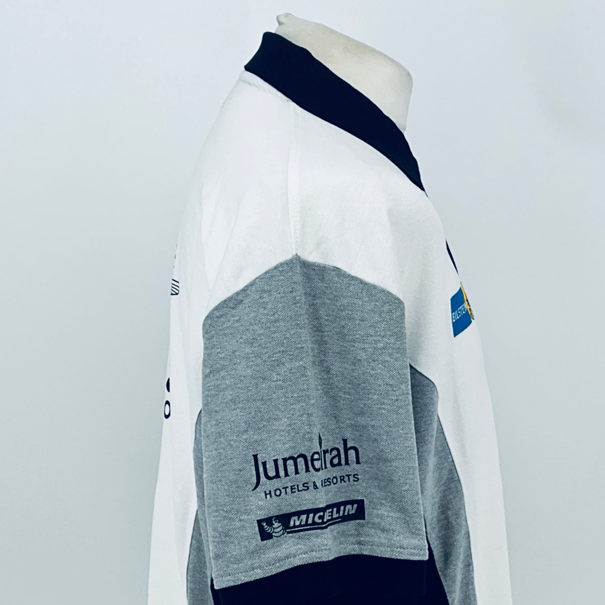 White polo shirt side view with navy collar and gray sleeve panel, Jumeirah and MICHELIN logo