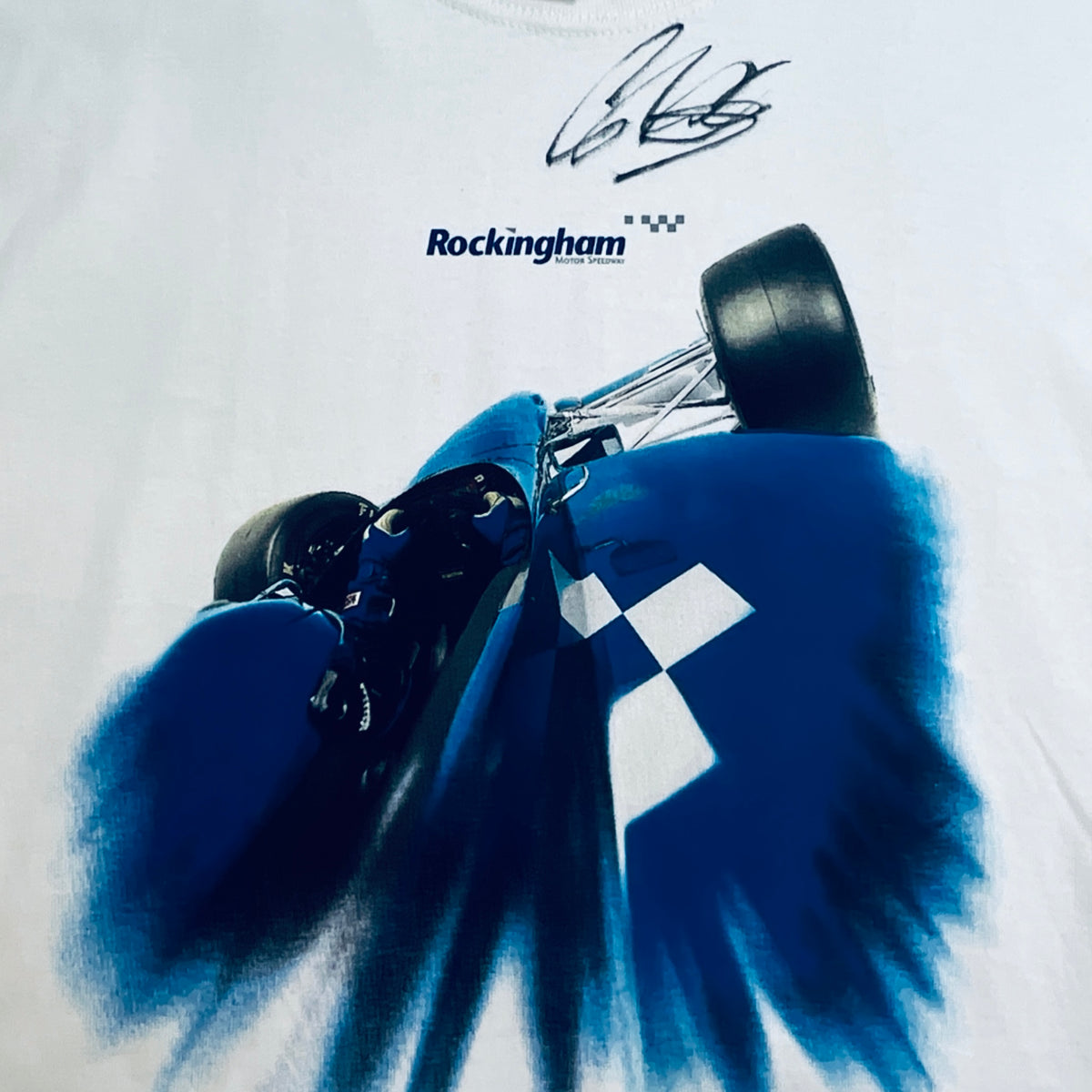 White T-shirt close-up: blue car graphic with Rockingham text and signature