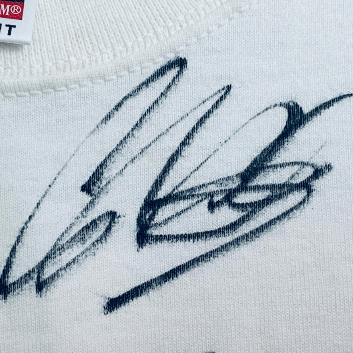 White T-shirt detail: blue signature-style autograph print on chest