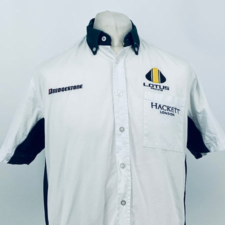 White short-sleeve button shirt with dark collar, chest pocket, and racing logos