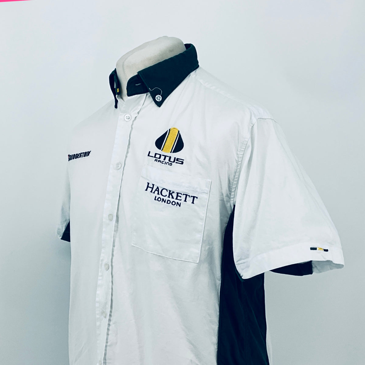 White short-sleeve button shirt with dark collar and front chest pocket logos