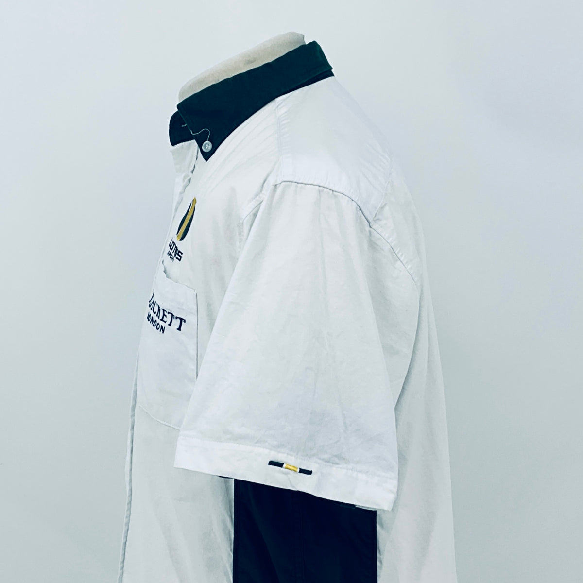 White short-sleeve button shirt with dark collar and sleeve logo patch on side view