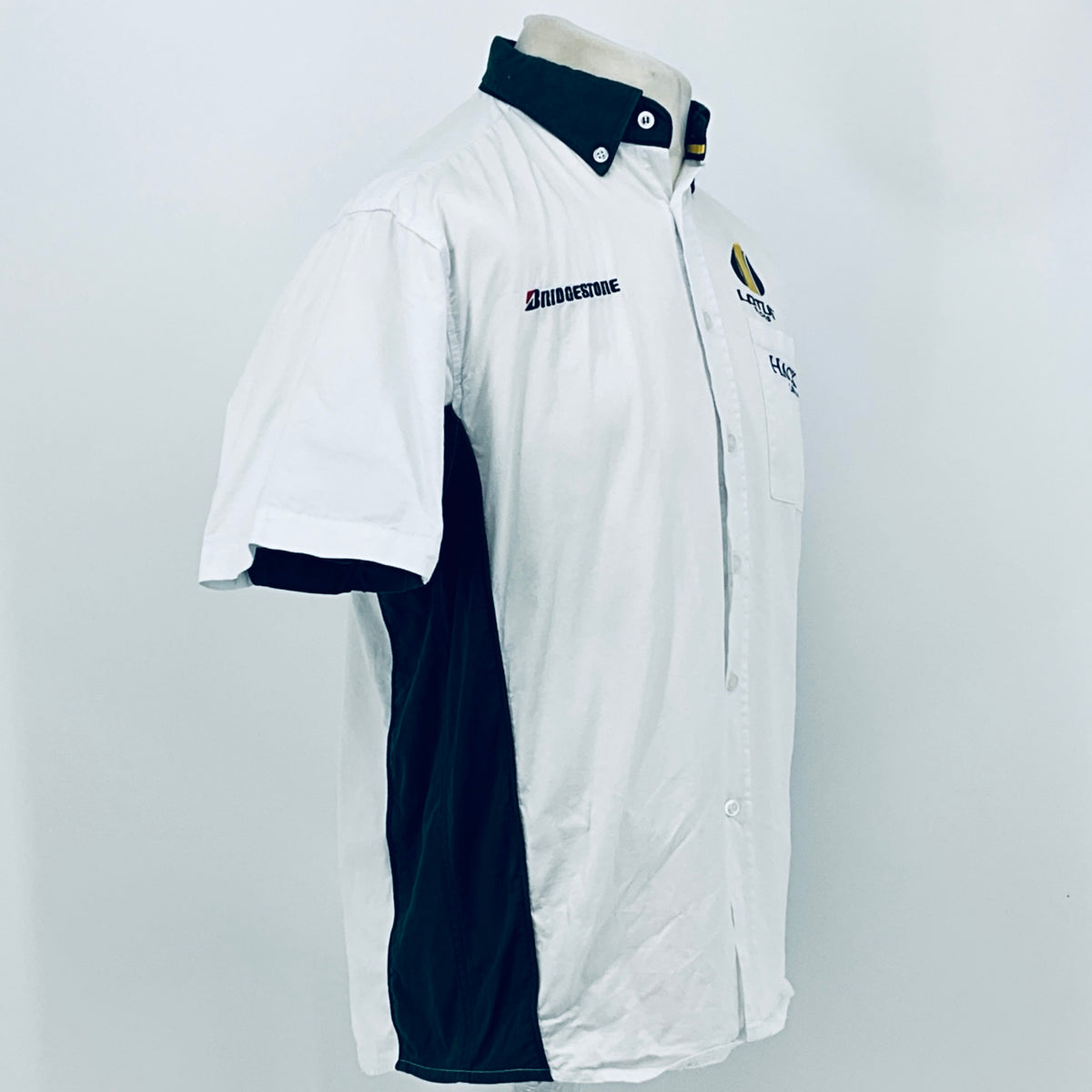 White short-sleeve button shirt with dark collar and side panel on angled side view