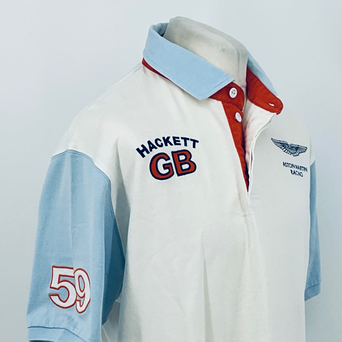 White and light blue polo shirt with HACKETT GB logo and Aston Martin Racing crest