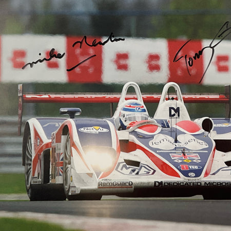 Two racing cars on a track with visible branding and signatures.