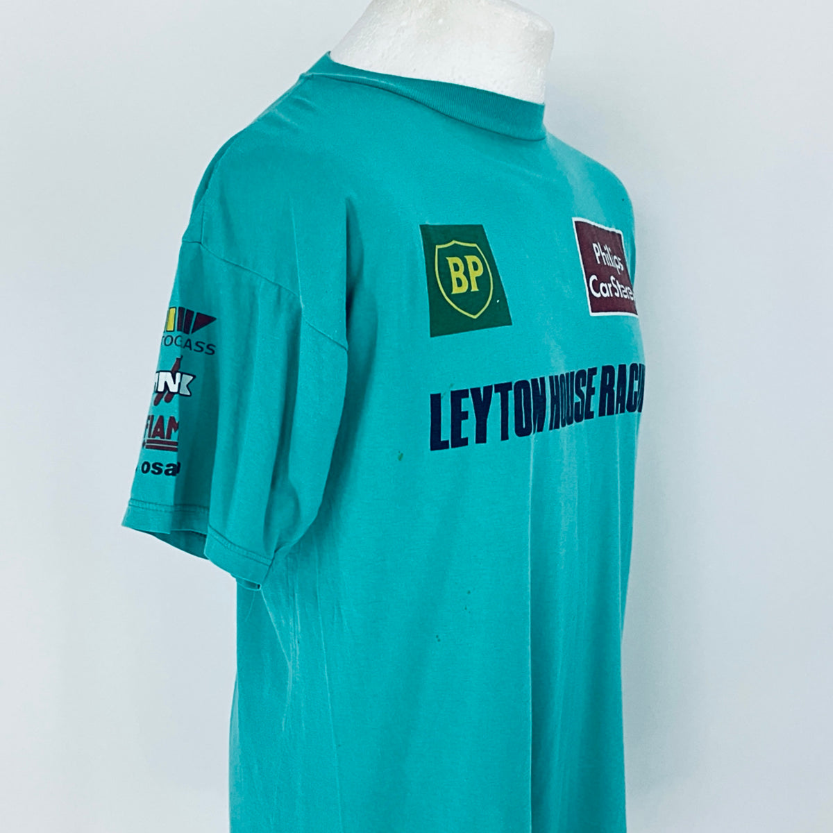 Teal racing shirt with various logos on a white background