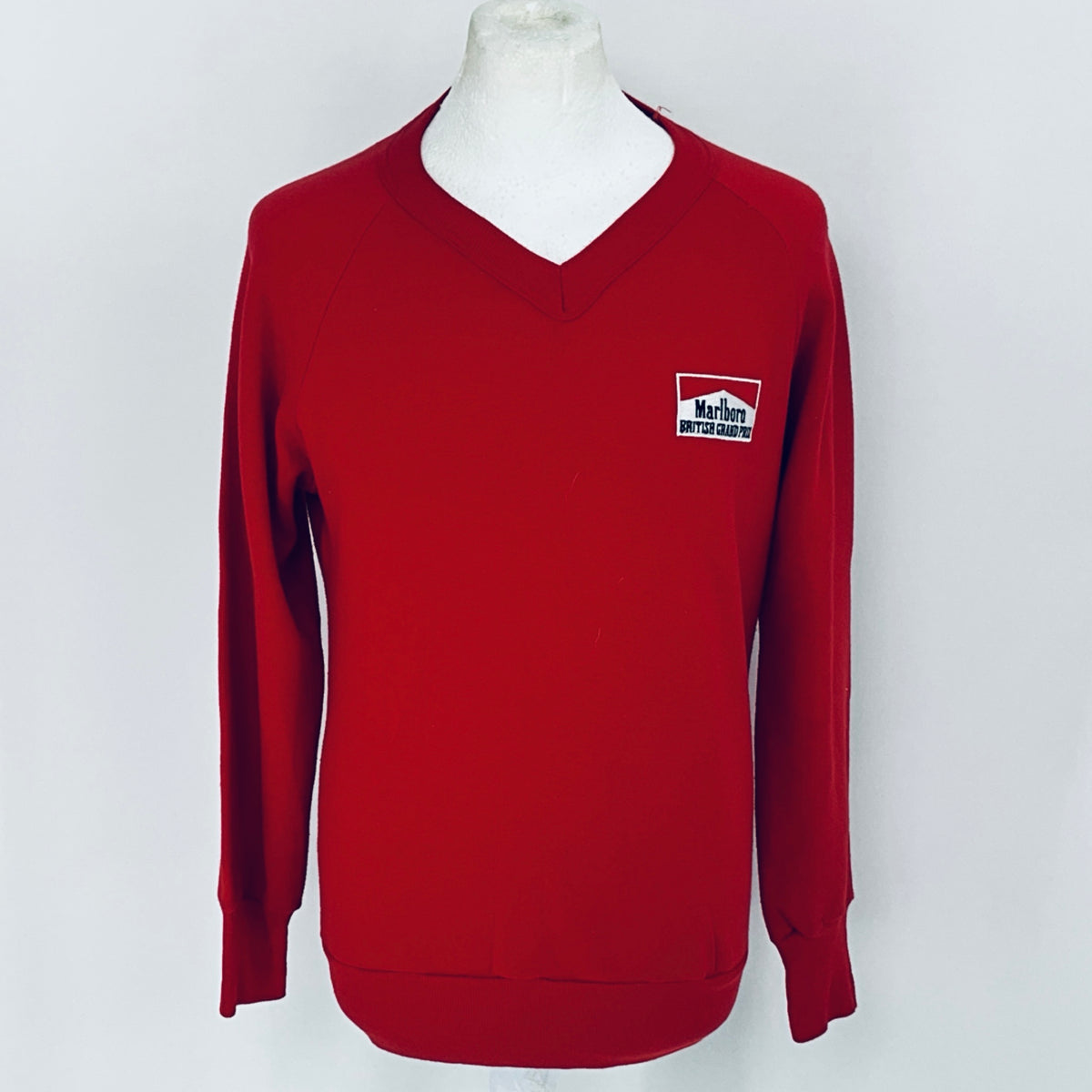 Red sweater with a logo on a mannequin against a white background