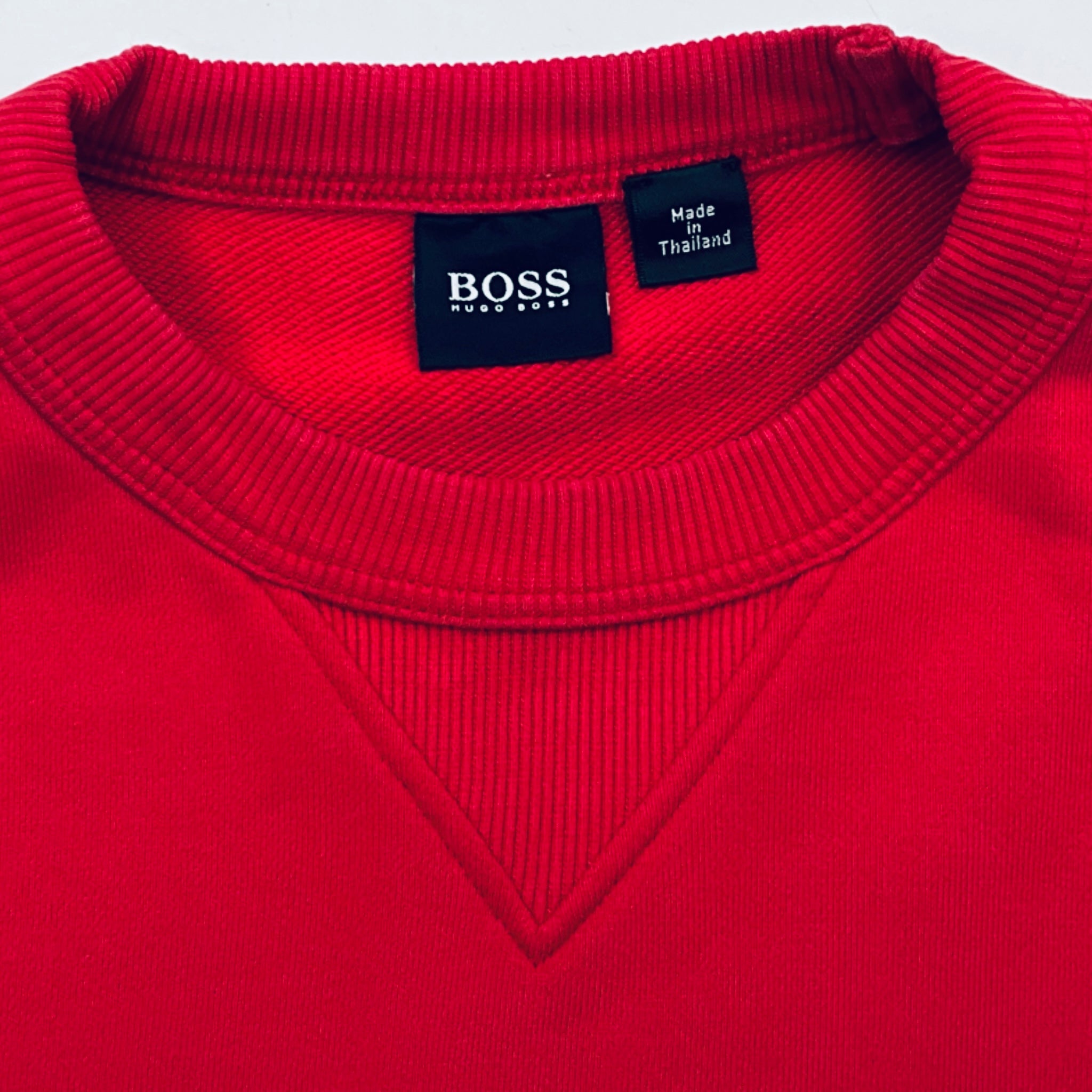 Close-up of a red sweater with a Boss label on a white background