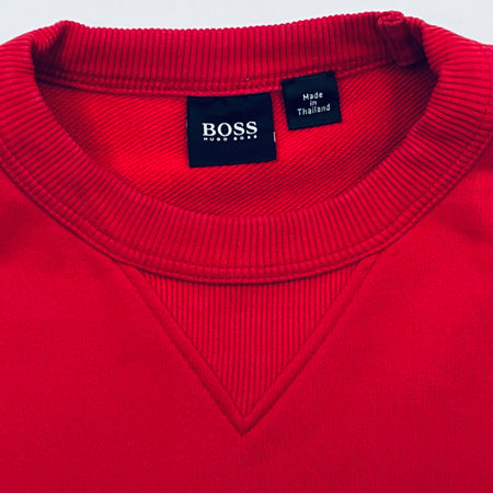 Close-up of a red sweater with a Boss label on a white background